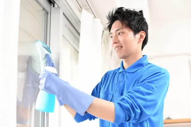 窓の清掃をしている青い服の作業員