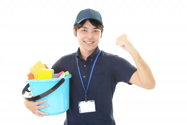 スポンジなどの清掃道具が入ったバケツを左手で小脇に抱えて右手でガッツポーズをする帽子を被りポロシャツを着た男性作業員