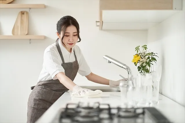 キッチンの水回りを掃除しているエプロンをした女性