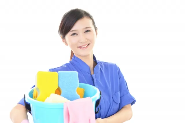 掃除用具の入ったバケツを両手に持っている笑顔の女性作業員