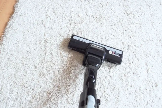 白いカーペットを掃除している掃除機のヘッド部分のアップ