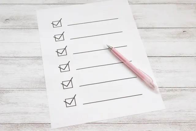 白い机の上に紙のチェックリストとえんぴつが置いてある