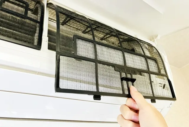 家庭用エアコンのフィルターを外しているところ