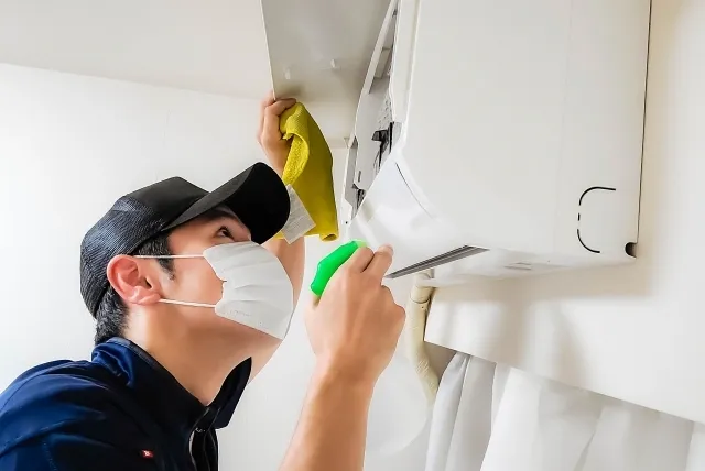 家庭用エアコンをスプレーで清掃している男性作業員